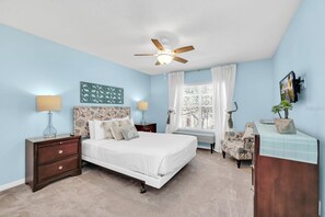 A bedroom with a bed, nightstands, a desk, a ceiling fan, and a window with curtains. - Luxury 6 Bedroom Pool Home Near Disney (Kissimmee)