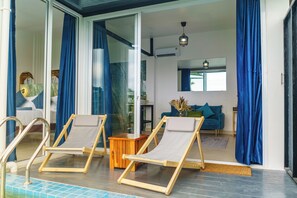 Un espace de vie moderne avec une piscine, deux chaises longues, un canapé et une table basse.