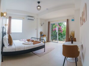 Une chambre d’hôtel avec un lit, une table, une chaise, une fenêtre et une vue sur la verdure.