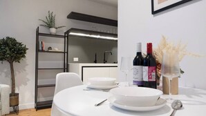 A dining area with a round table, white plates, and wine bottles. - Luxury CBD LaTrobe Retreat 1BR Apt w/Pool & Gym (Docklands)