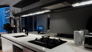 A modern kitchen with a built-in gas stove, a double sink, and a microwave. - Luxury CBD LaTrobe Retreat 1BR Apt w/Pool & Gym (Docklands)