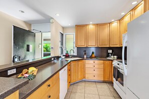 Eine moderne Küche mit Holzausstattung, einem eingebauten Backofen und einem Edelstahl-Spülbecken.