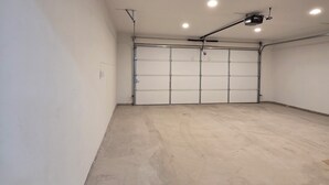 A spacious garage with a concrete floor, a ceiling-mounted projector, and a garage door.
