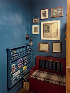 A room with a blue wall, a red bench, and a bookshelf with books. - Texan Cottage Getaway —Near UTSA, Six Flags, Seaworld; Family Recreation & Trail (San Antonio)