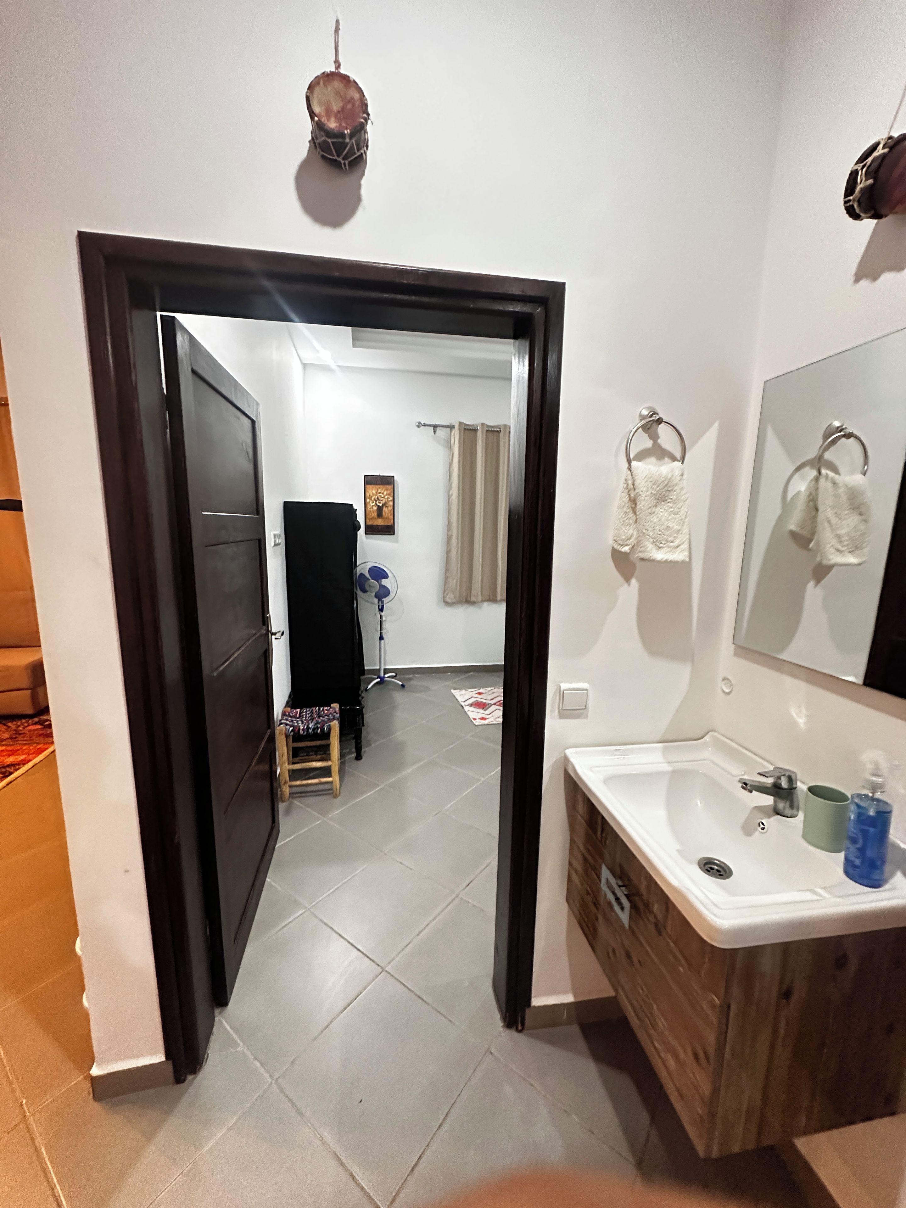 Een badkamer met een wastafel, spiegel en handdoekhouder.