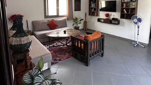 A living room with a sofa, coffee table, and a TV mounted on the wall. - Villa Sylvester, Essaouira (Essaouira)