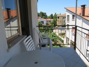 A balcony with a table and chairs, a view of neighboring buildings, and a clear sky. - Boho Apartment Oma Maria / HR-11059-03 by Interhome (Dracevac)