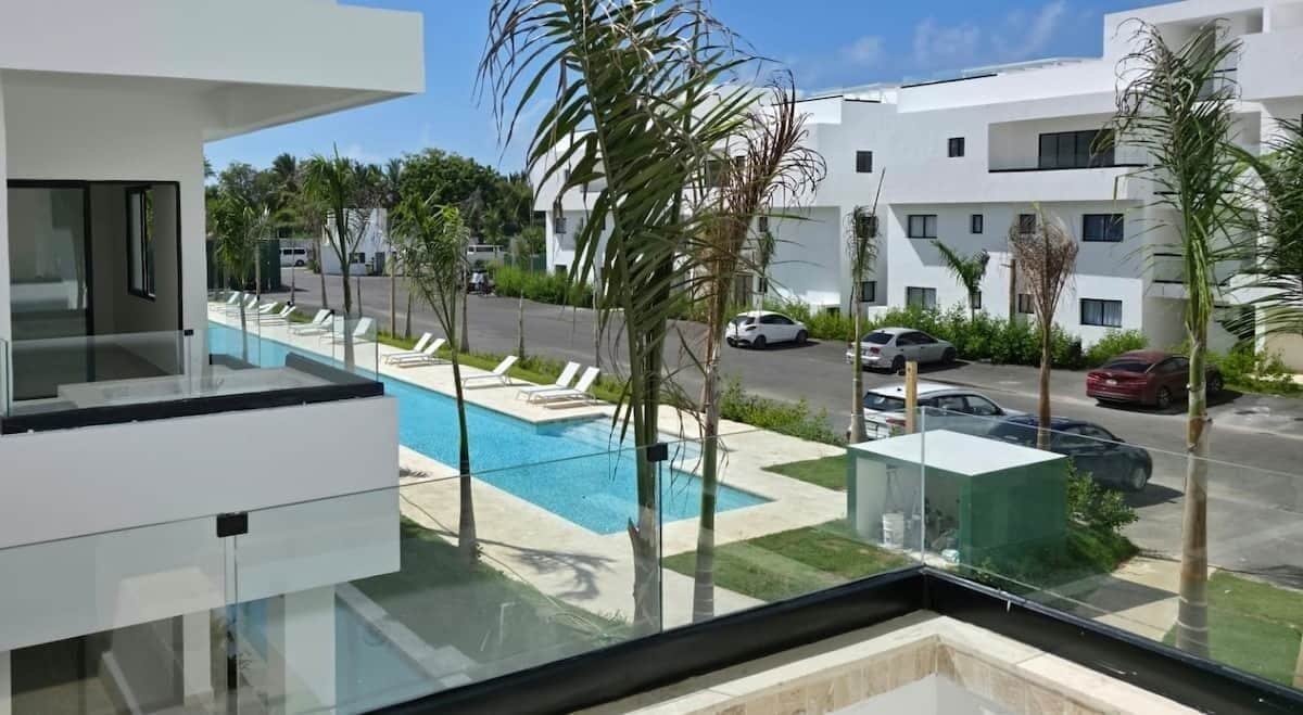 A modern building with a pool, lounge chairs, and a clear view of the street.