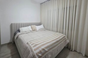 Ein Schlafzimmer mit Bett, Kopfteil und einem Vorhangfenster.