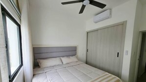 A bedroom with a bed, a ceiling fan, an air conditioning unit, and a door. - Apartment for Airbnb Punta Cana - ONA Resident 2BR (Punta Cana)