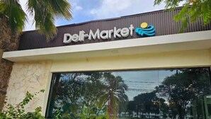 A building with a sign that reads 'Dei Market' and a large glass window. - Apartment for Airbnb Punta Cana - ONA Resident 2BR (Punta Cana)