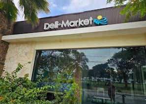 Ein Gebäude mit einem Schild, auf dem 'Dei Market' steht, und einem großen Schaufenster.