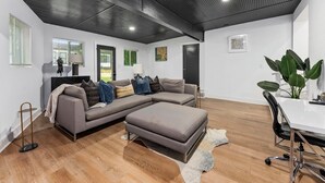 Ein modernes Wohnzimmer mit einer Eckcouch, einem Esstisch und einer großen Pflanze.
