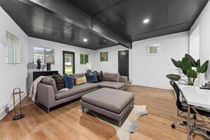 Ein modernes Wohnzimmer mit einer Eckcouch, einem Esstisch und einer großen Pflanze.