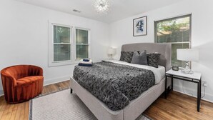 Ein Schlafzimmer mit einem Bett, einem Sessel, einem Nachttisch und einer Deckenleuchte.