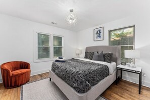 Ein Schlafzimmer mit einem Bett, einem Sessel, einem Nachttisch und einer Deckenleuchte.