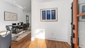 Ein modernes Interieur mit Essbereich, Holzboden und einem gerahmten Kunstwerk an der Wand.