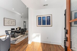 Ein modernes Interieur mit Essbereich, Holzboden und einem gerahmten Kunstwerk an der Wand.
