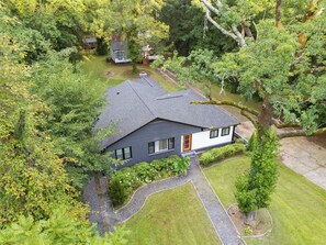 A two-story house with a dark roof, surrounded by dense greenery and a well-maintained lawn. - Your Home Away From Home | Business & Travel Ready (Atlanta)
