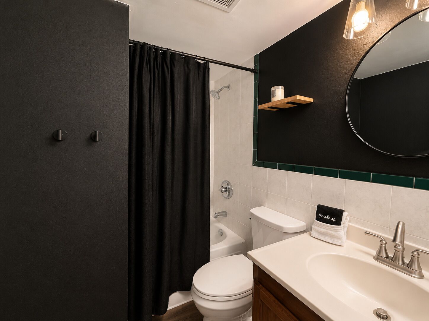 Et moderne badeværelse med bruser, toilet, vask og et spejl over vasken.