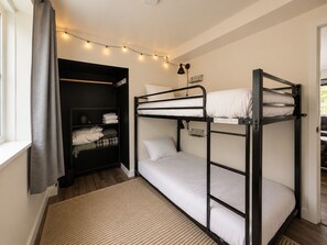 A bunk bed room with a window, a shelf with folded clothes, and string lights. - Base Camp Breckenridge | Aspens · Hot Tub · Dogs (Breckenridge)