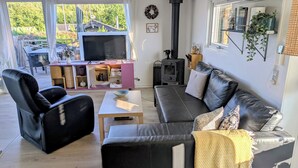 Ett mysigt vardagsrum med en svart lädersoffa, ett soffbord i trä och en tv.