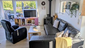 Ein gemütliches Wohnzimmer mit einer schwarzen Ledersofa, einem Holztisch und einem Fernseher.