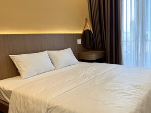 A hotel room with a bed, a bedside table, a mirror, and a window with curtains. - Han House's Apartment 2 (Da Nang)