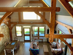 Ein großzügiger Loft mit hohen Decken, freiliegenden Holzbalken und großen Fenstern mit Blick ins Freie.