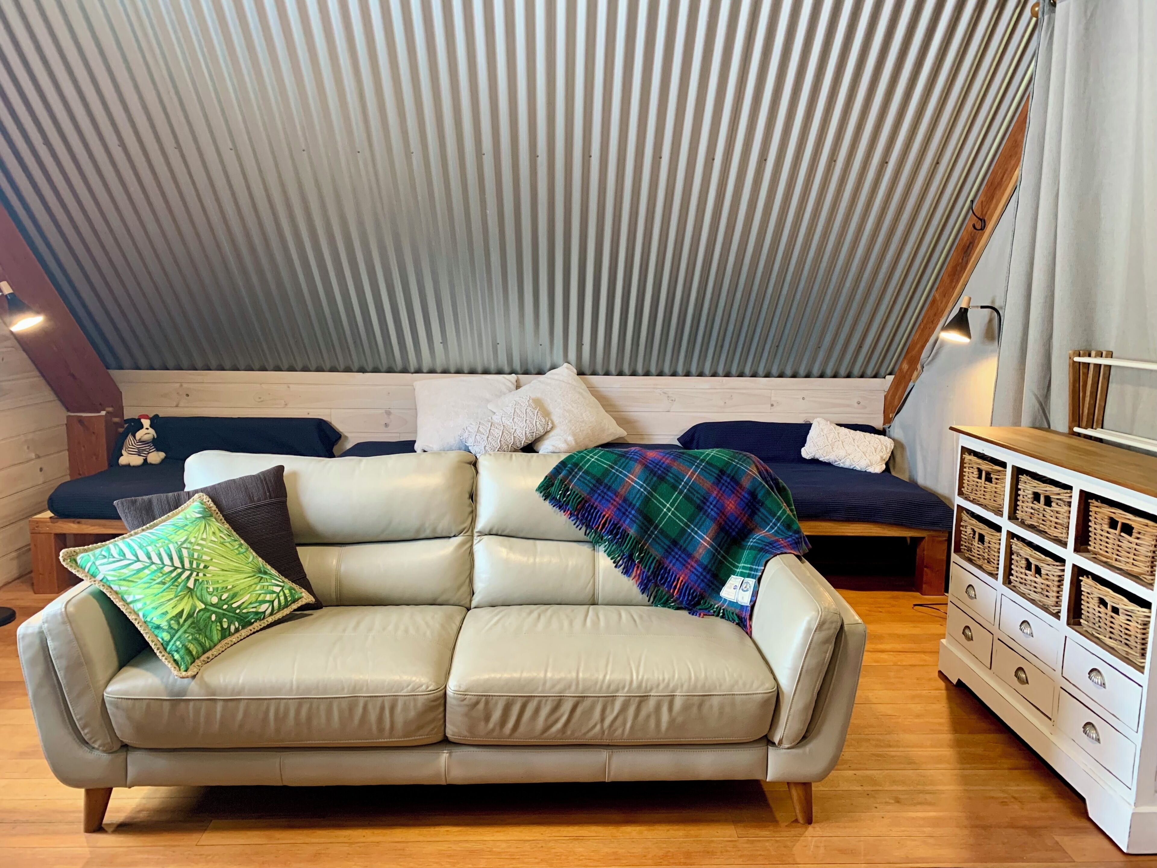 A cozy room with a high ceiling, a sofa, a wooden dresser, and a small dog figurine.