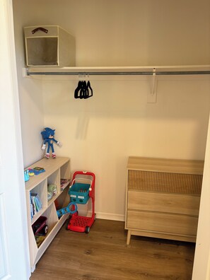 A child's room with a wooden dresser, a shelf with toys, and a red toy car. - Spacious 3BR House in Frisco - Minutes from Top Event Attractions (Frisco)