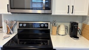 A kitchen with a microwave, oven, coffee maker, and utensils. - Spacious 3BR House in Frisco - Minutes from Top Event Attractions (Frisco)