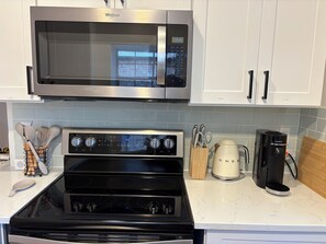 A kitchen with a microwave, oven, coffee maker, and utensils. - Spacious 3BR House in Frisco - Minutes from Top Event Attractions (Frisco)