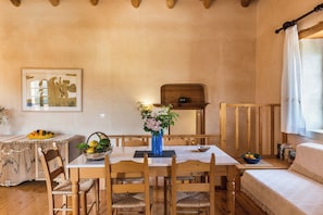 A dining area with a wooden table, chairs, and a vase of flowers. - Kamares Private Pool stone Villa (Macheri)