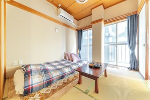 Quarto com cama, mesa e janela com cortinas.