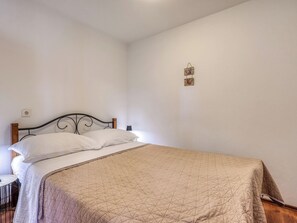 Ein Einzelbett mit Kopfteil, Nachttisch und Wandleuchte.