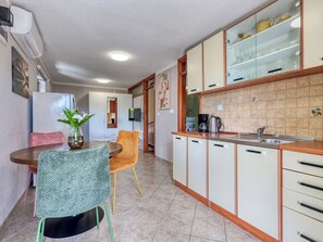 Eine kompakte Küche mit Essbereich, ausgestattet mit einer Kaffeemaschine, einem Spülbecken und einem Schrank mit Glastüren.