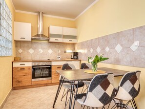 Eine moderne Küche mit Essbereich, ausgestattet mit Herd, Backofen und einer Kaffeemaschine.