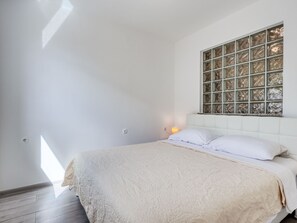 Ein Schlafzimmer mit einem großen Bett, einem Fenster mit dekorierter Scheibe und einer Wandleuchte.