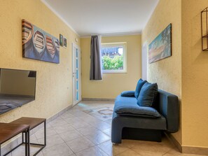 A room with a sofa, a table, and artwork on the walls. - Apartment Duema by Interhome (Opatija/Pobri)