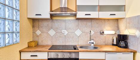 A compact kitchen with a stove, oven, sink, and a coffee maker.