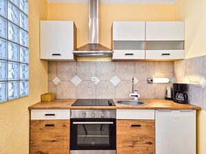 A compact kitchen with a stove, oven, sink, and a coffee maker. - Apartment Duema by Interhome (Opatija/Pobri)