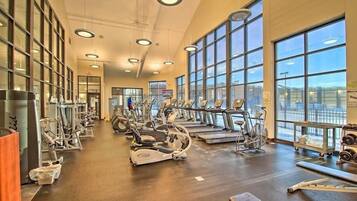Un gimnasio con máquinas de cardio, equipo de levantamiento de pesas y grandes ventanales.
