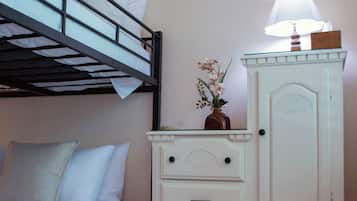 Een stapelbed met witte beddengoed en een dressoir met lades en een spiegel.