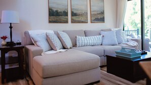 En stue med sofa, puder, en lampe og kunst på væggen.
