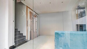 A modern interior with a glass door entrance, a staircase, and a fan on the ceiling. - Townhouse Bairhana Road Prayagraj (Prayagraj)