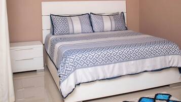 A bedroom with a bed, nightstand, air conditioning unit, ceiling fan, and a patterned rug.