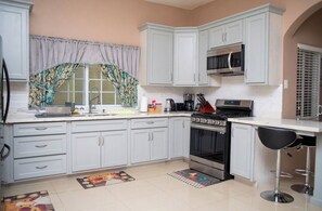 Una cucina con mobili bianchi, un forno a microonde, un fornello e una macchina da caffè.