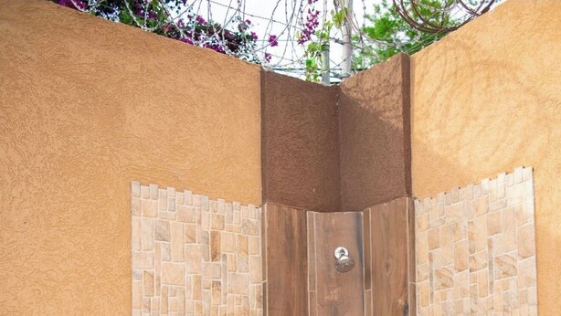 A corner shower with a wooden door and mosaic tile walls. -  Entire townhouse in Montego Bay, Jamaica (Montego Bay)