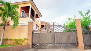 A gated residential area with a two-story house, a balcony, and a palm tree. -  Entire townhouse in Montego Bay, Jamaica (Montego Bay)